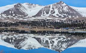 Placa oficial del 40° aniversario de Caviahue sobre un paisaje de montaña, detallando la fecha y hora del acto protocolar en el Centro de Convenciones.