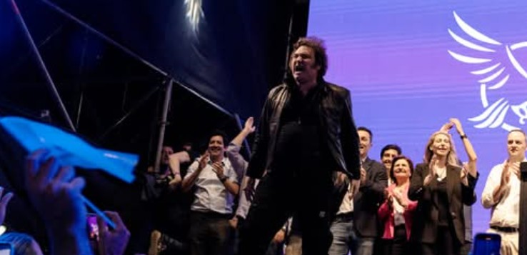 Fotografía del presidente Javier Milei con una casaca de cuero en la caja de una camioneta, dando un discurso con megáfono frente a una multitud en Córdoba.