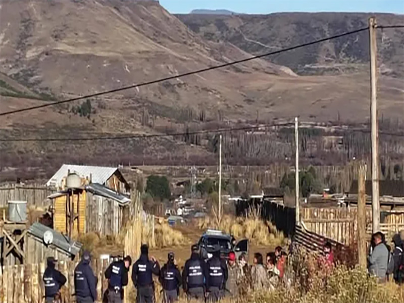 Vista de un asentamiento precario bajo un fuerte cerco policial o una imagen que represente conflicto por la tierra.