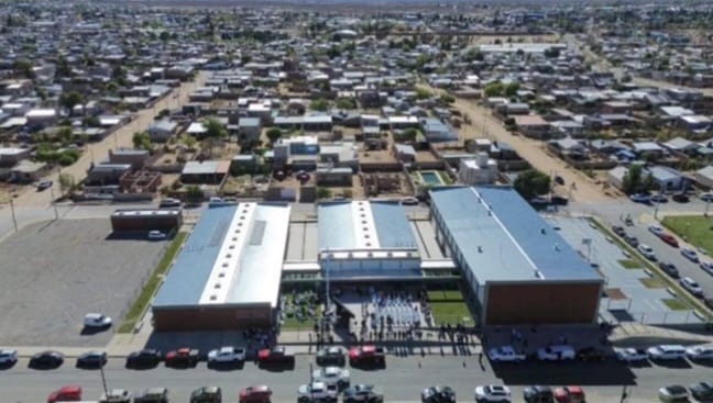 El gobernador Rolando Figueroa cortando la cinta inaugural junto a la comunidad educativa de la Escuela 22 en Plaza Huincul.