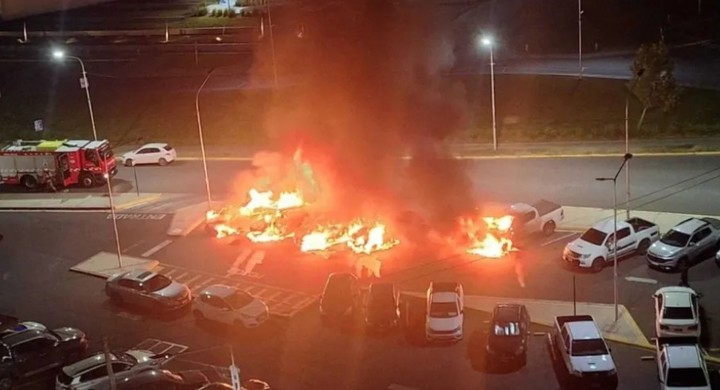 Efectivos policiales y peritos de bomberos recolectando muestras entre los restos de los vehículos incendiados frente a la Ciudad Judicial.
