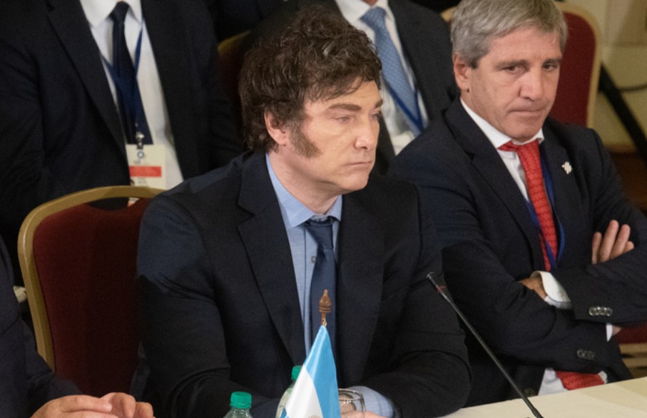 Javier Milei y Donald Trump dándose la mano o en una reunión formal, con banderas de Argentina y Estados Unidos de fondo.
