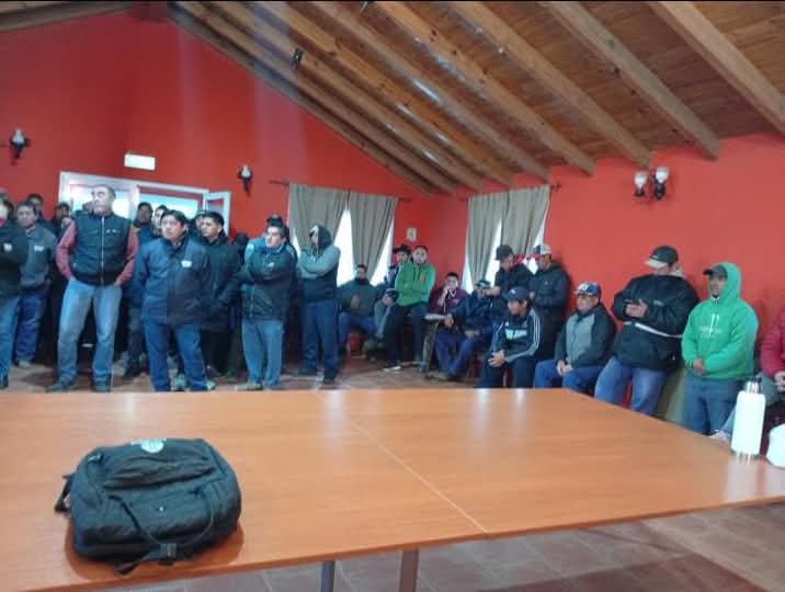 Grupo de trabajadores municipales manifestándose frente al edificio municipal de El Huecú, con pancartas.